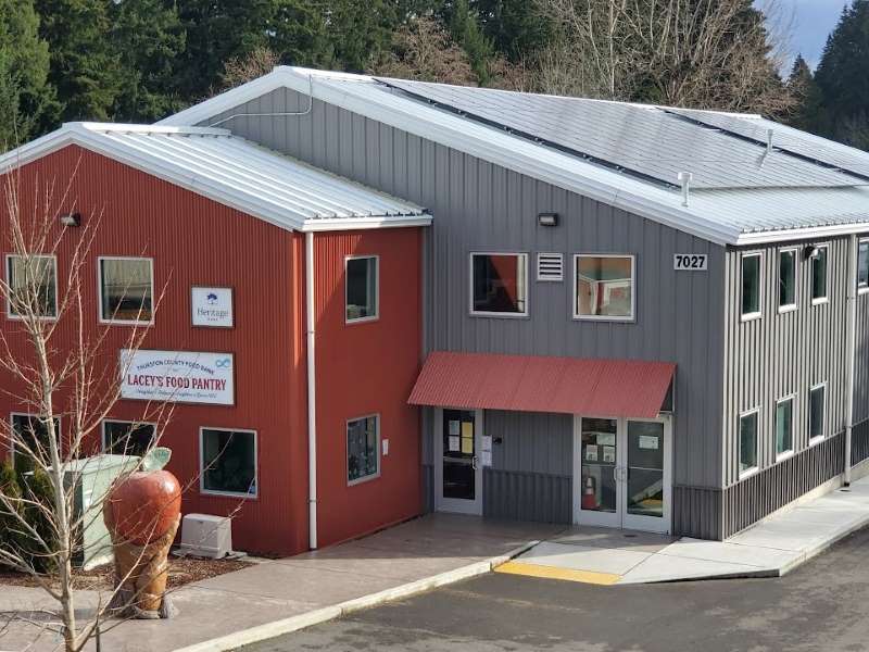 Shows Lacey's Food Pantry with solar panel array and community art sculpture, a young and old hand cradling an apple as the earth.