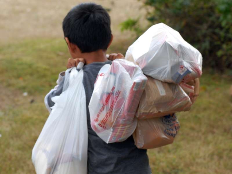 Shows a child taking Summer Lunch food bags home in 2013. These meals were taken home; some are eaten on site.