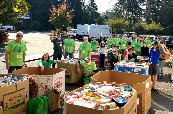 Thurston County Food Project volunteers shown delivering and sorting bi-monthly food drive donations outside in the warehouse parking lot.